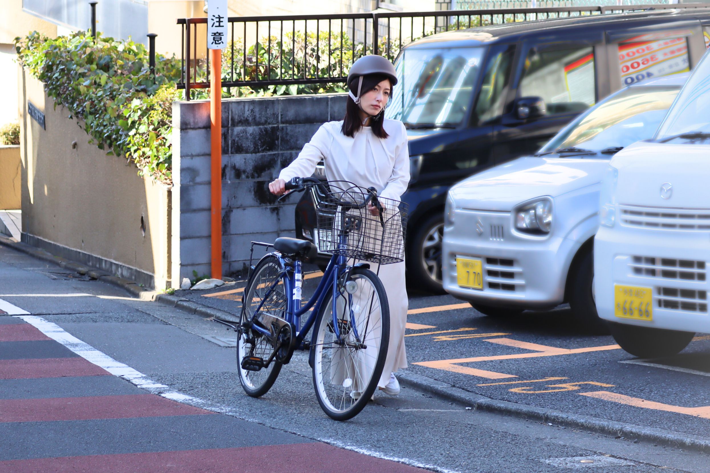 坂道で自転車を押して歩く女性